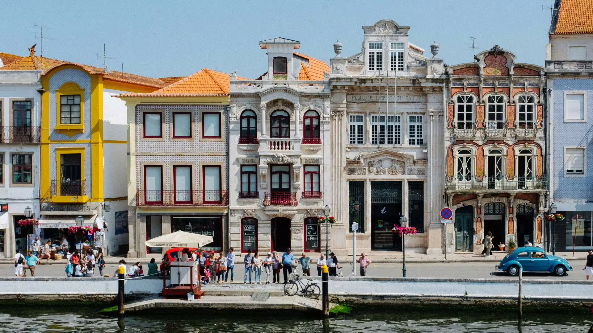 Colorful Art Nouveau buildings line the picturesque canal in Aveiro, Portugal, bustling with tourists.