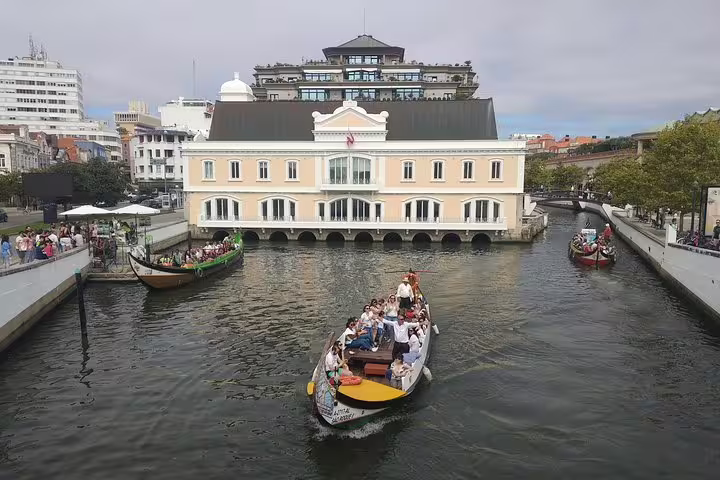 Tourists enjoy a boat ride on the picturesque canals of Aveiro, surrounded by charming architecture and vibrant scenery.