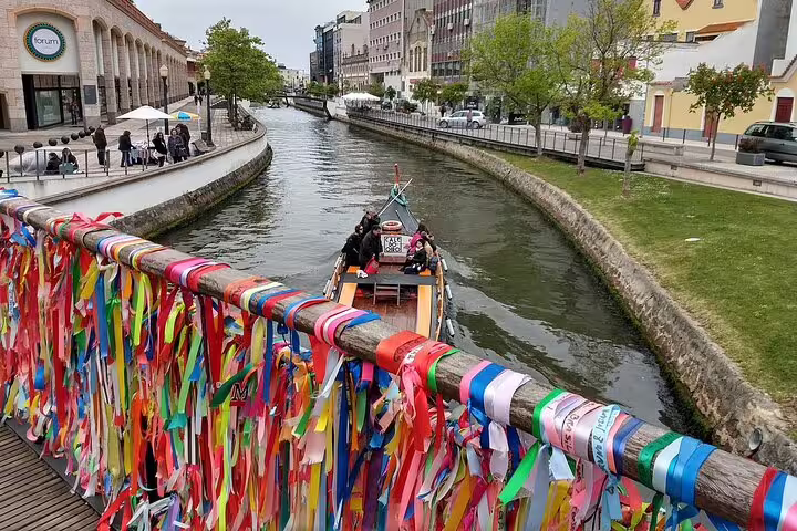 Vibrant ribbons adorn a bridge over Aveiro's canal with a moliceiro boat in view on a private full-day tour from Porto.
