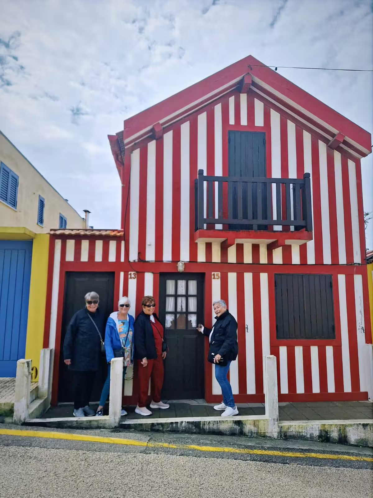 Tourists in front of a traditional striped Costa Nova house, highlighting colorful architecture on Aveiro city tour.