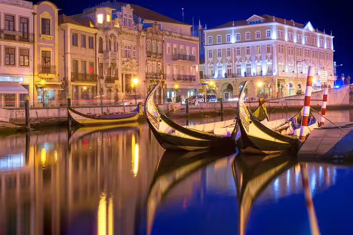 Illuminated gondolas on a tranquil canal in Aveiro at night, highlighting picturesque architecture for private Lisbon to Porto transfers.