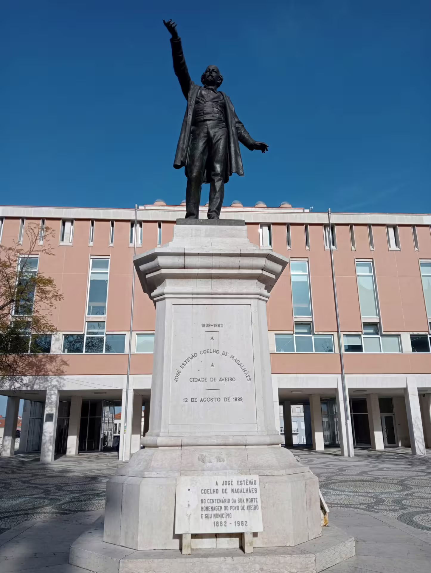 Statue of a historical figure in Aveiro against a modern building backdrop, perfect for cultural tours.