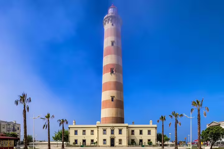 Iconic red and white striped lighthouse in Aveiro, Portugal, under a clear blue sky, featured on a private tour from Lisbon.