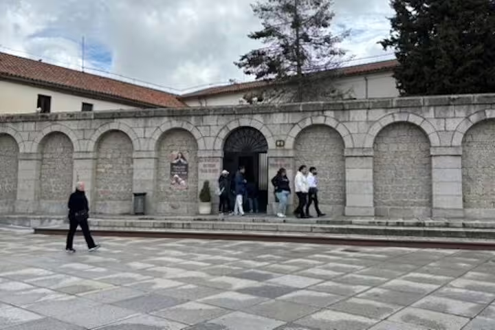 Arched courtyard entrance in Ávila with visitors, part of the half-day private minivan tour itinerary