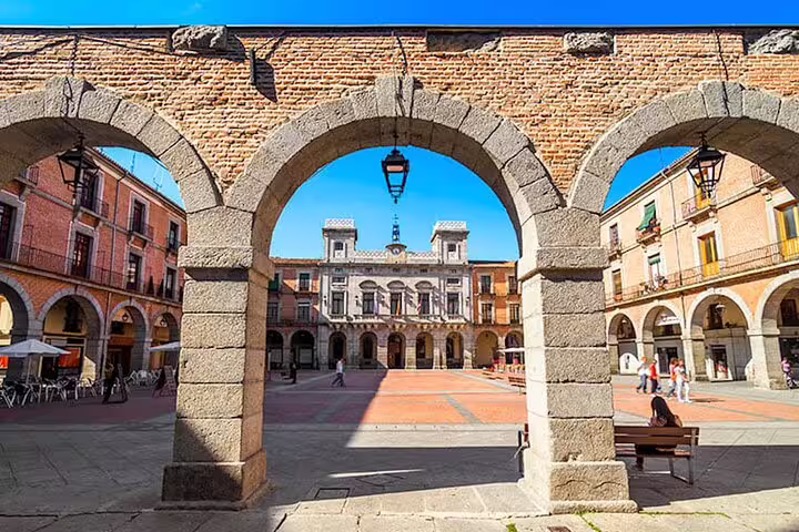Ávila Plaza del Mercado Chico seen through stone arches, stop on half-day private minivan tour