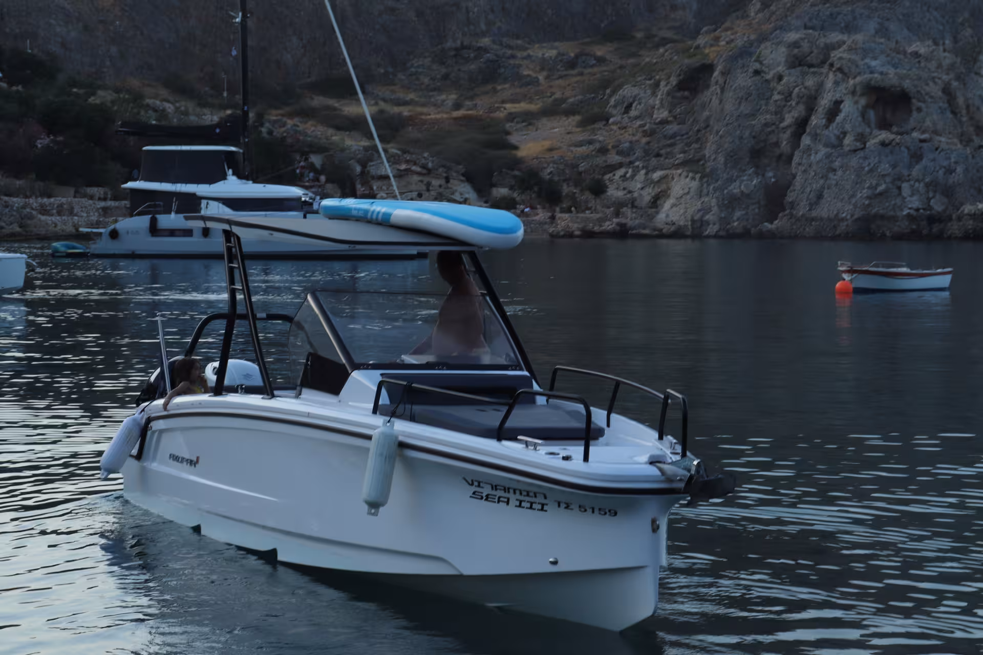 Axopar 25 CT sunset cruise boat gliding through a calm rocky bay, ideal for private evening sea tour