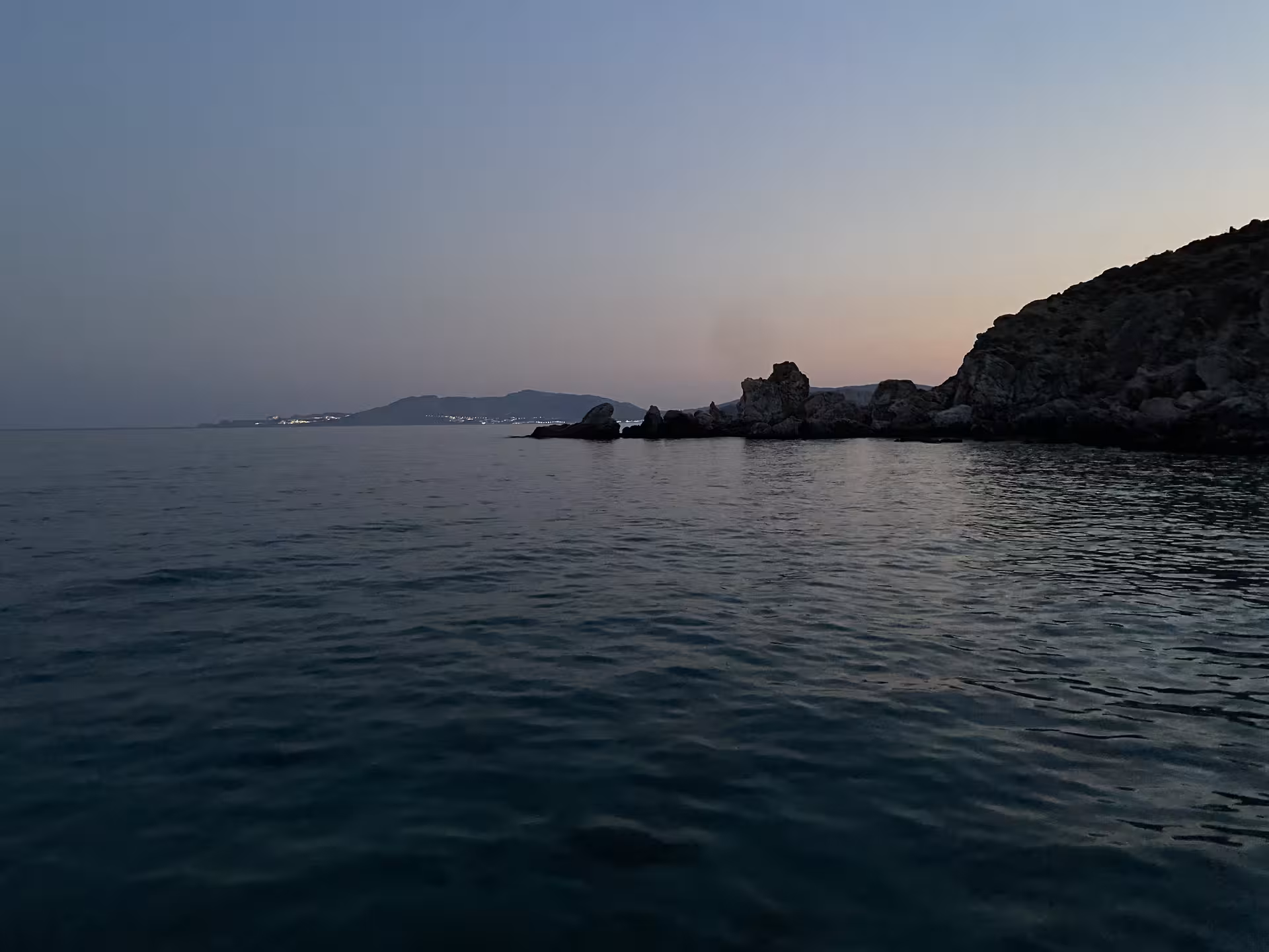 Calm twilight sea by rugged cliffs and distant islands, scenic Axopar 25 CT sunset cruise experience