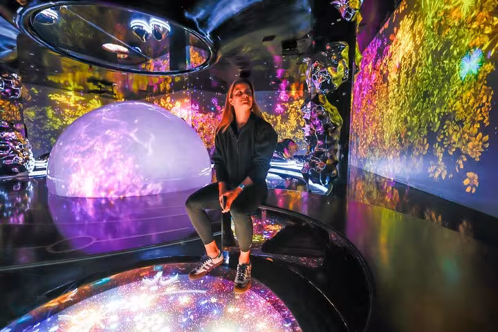 Person seated in an immersive, colorful digital space at Aya Universe Dubai, featured in a private videography tour.