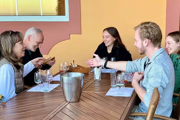 Group enjoying Azeitão cheese workshop and wine tasting on a sunny terrace during a private Sesimbra tour experience.