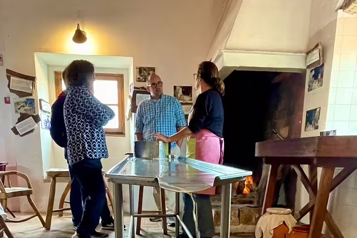 Participants engage in a hands-on Azeitão cheese workshop, learning traditional methods beside a rustic fireplace in Portugal.