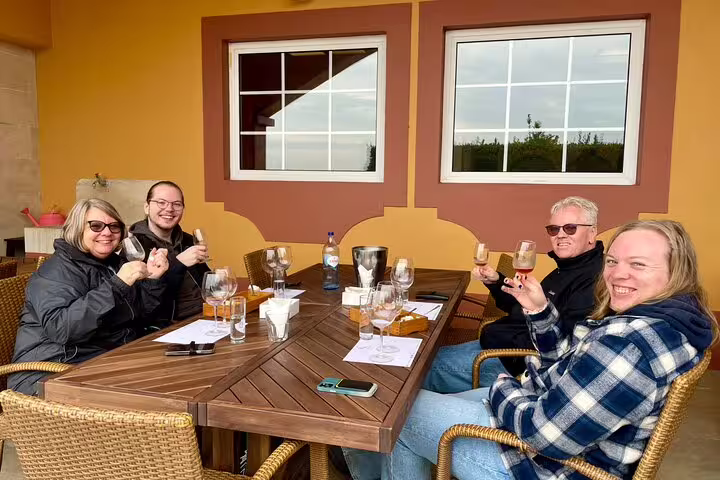 Group enjoying Azeitão cheese workshop with wine tasting outdoors on a sunny Sesimbra tour, showcasing local flavors and culture.