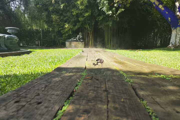 Wooden path leading to a serene garden sculpture, perfect for a peaceful stroll during the Setúbal Moscatel wine tour.
