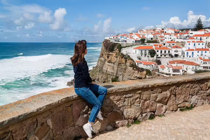 Woman enjoying scenic coastal view of Azenhas do Mar village near Sintra, showcasing stunning cliffs and ocean waves.