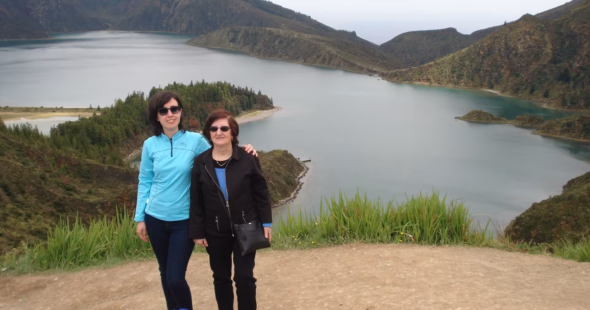 Travelers at an Azores crater lake viewpoint with forested islets, a must-see stop on a 4-day island adventure tour