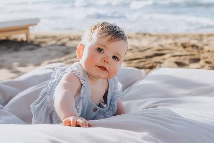 Adorable baby enjoying the beach with gentle waves in the backdrop during a Heraklion photoshoot.