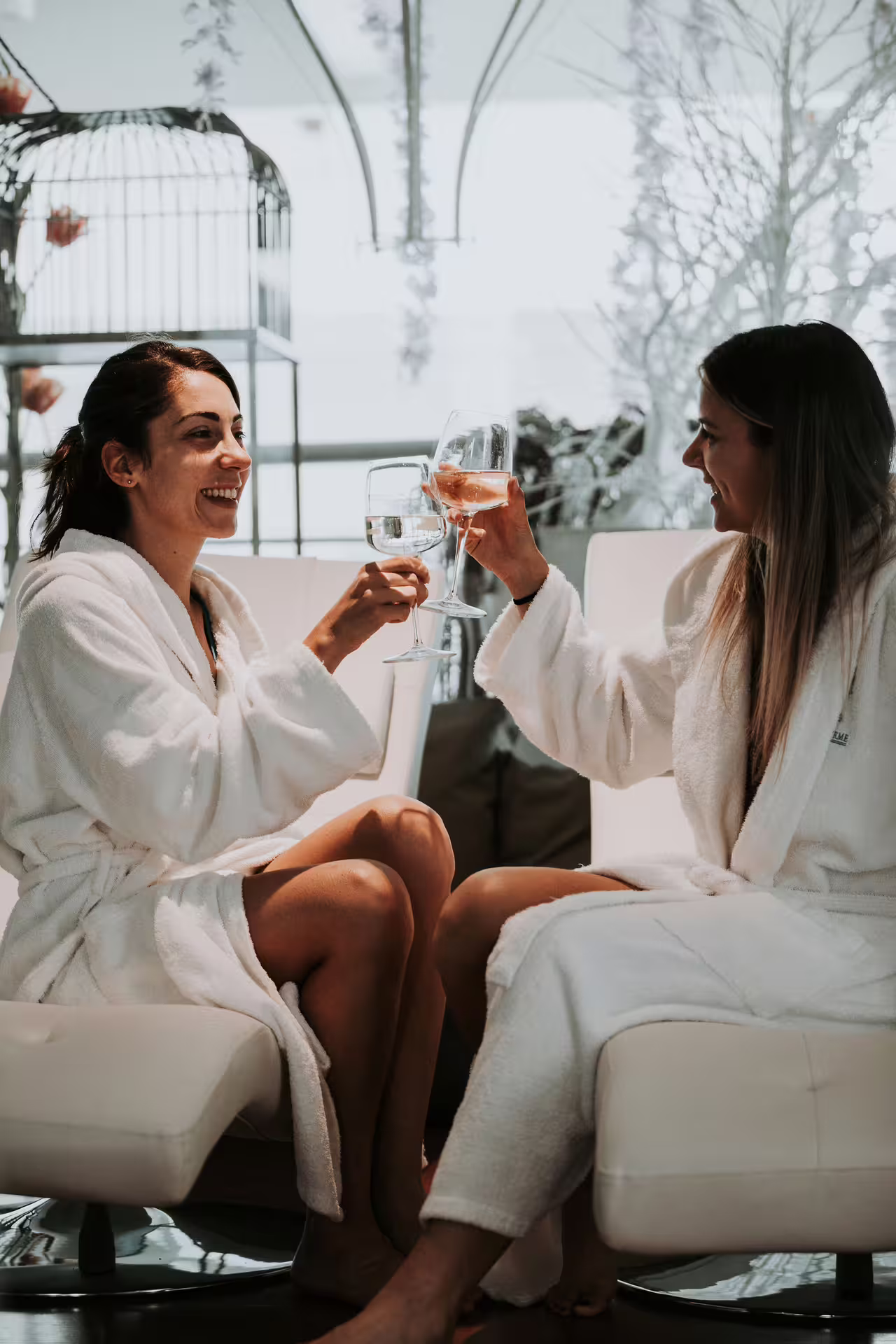 Two women in bathrobes toast aperitif at Bagno di Romagna spa before 2-hour thermal pool entry