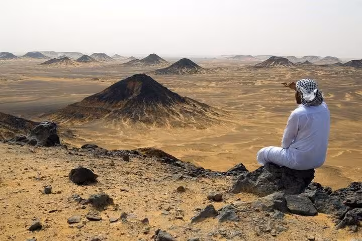 Traveler overlooking Black Desert volcanic hills near Bahariya Oasis on a 3-day eco camping tour in Egypt
