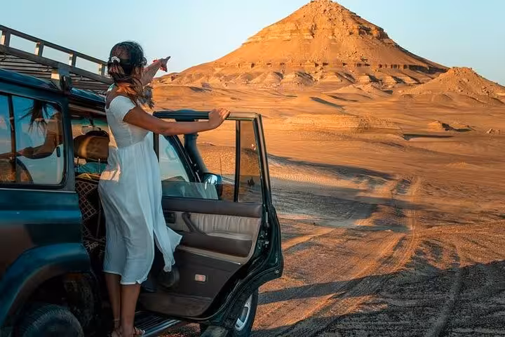 Traveler steps from 4x4 at sunset in Bahariya Oasis desert, Egypt, on a 3-day eco camping safari tour
