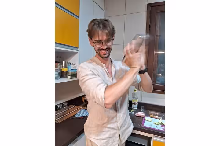 Participant joyfully shaking a cocktail shaker in a lively Bahian cooking class in Salvador.