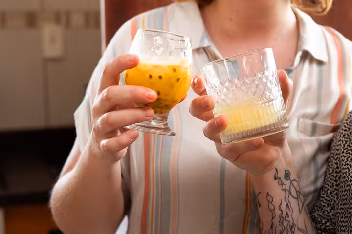 Participant enjoying tropical cocktails during a Bahian cooking class in Salvador, featuring vibrant passion fruit drinks.