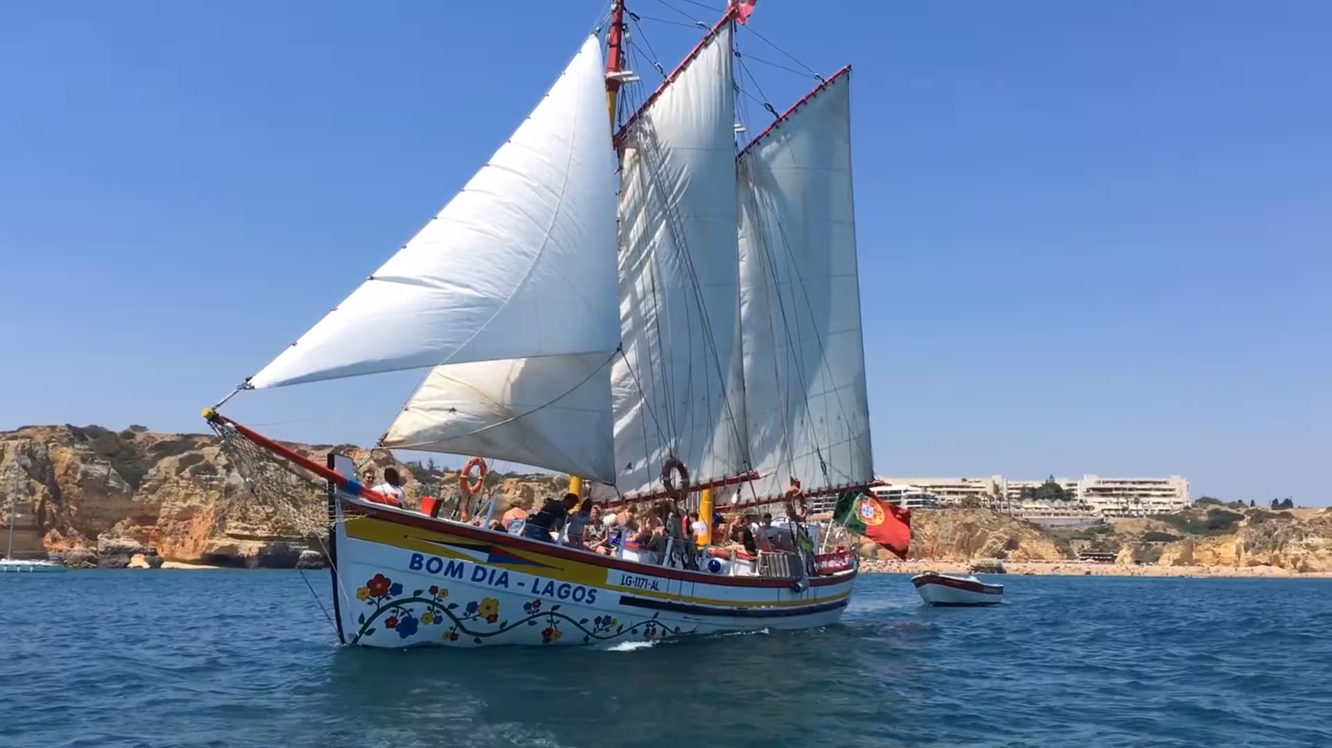Traditional sailing boat Bom Dia Lagos glides past golden Algarve cliffs on a Baia de Lagos coastal cruise tour