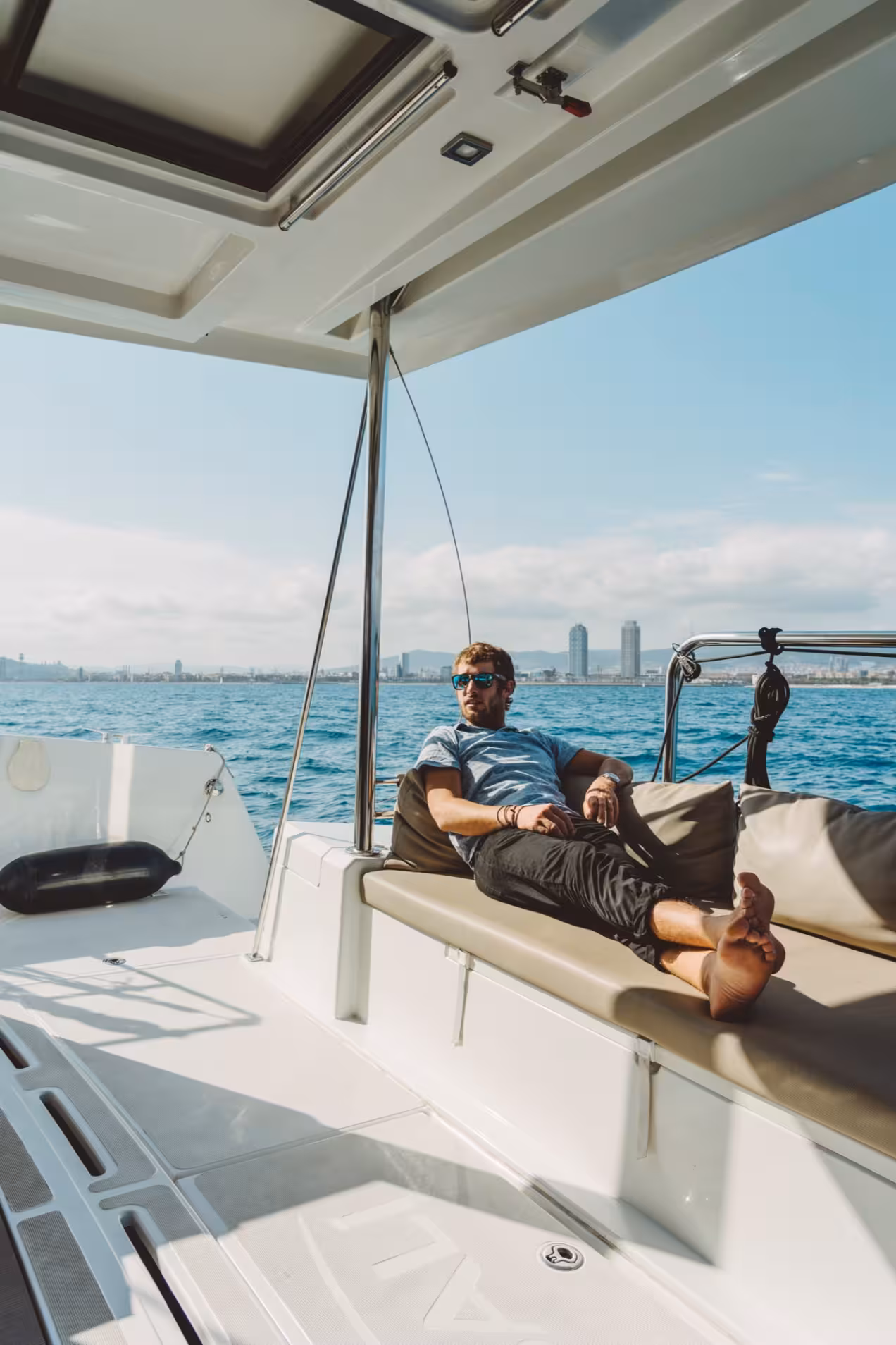 Relaxing on shaded lounge deck of Bali 4.1 luxury catamaran on a 3-hour private Barcelona sailing tour