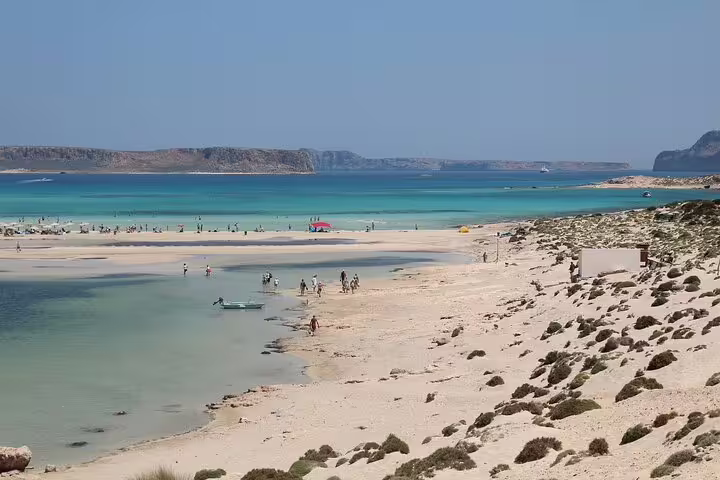 Tourists enjoy the pristine sands and turquoise waters of Balos Lagoon, perfect for a private tour and relaxation.