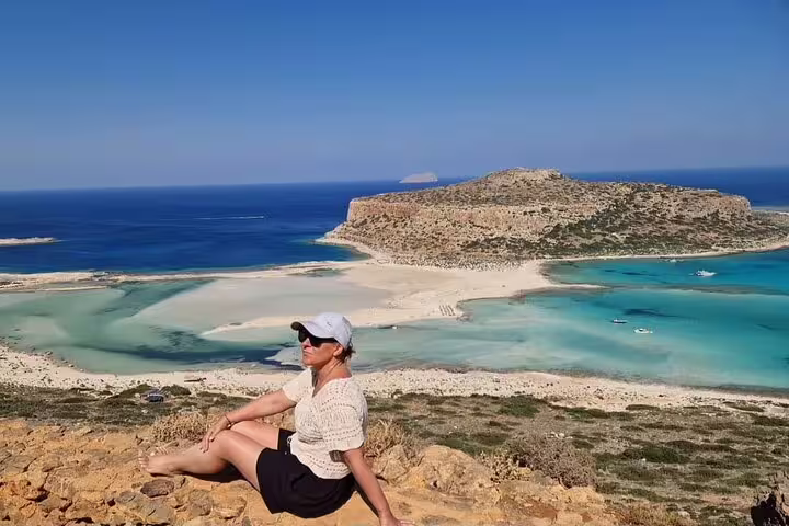Woman relaxing with a scenic view of Balos Lagoon's crystal-clear waters and sandy beaches, perfect for a private tour.