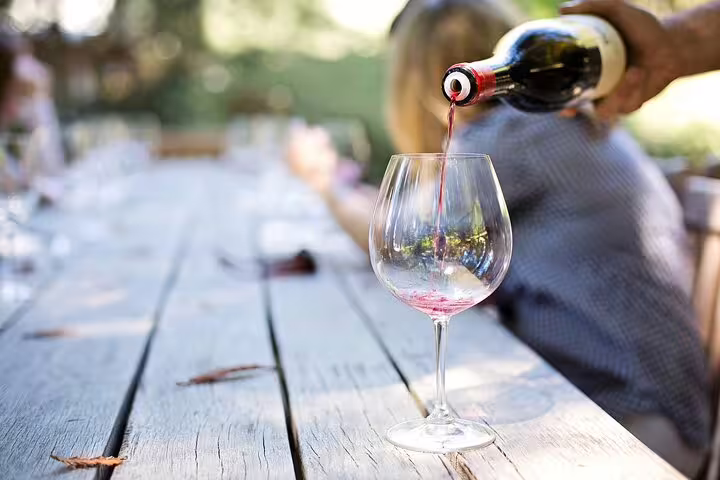 Red wine is elegantly poured into a glass, setting the scene for a delightful wine tasting experience on tour.