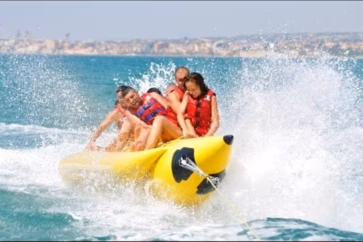 Friends riding a banana boat in Hurghada on the Red Sea, thrilling water sports tour with transfers