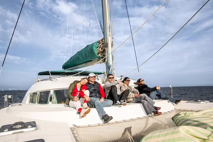 Group enjoying a scenic Barcelona private catamaran cruise with snacks and cava, perfect for a relaxing sunset experience.