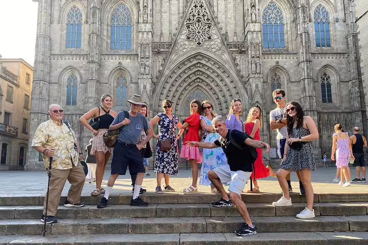 Group of visitors posing in front of the Gothic architecture of Barcelona Cathedral.
