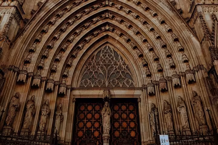 Intricate Gothic facade of the Barcelona Cathedral, showcasing detailed stone carvings on a guided city tour.