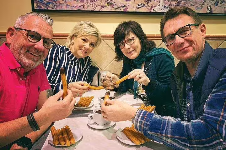 Group enjoying churros and hot chocolate, part of a Food & Drink Tasting Private Tour in Barcelona with Sagrada Familia visit.