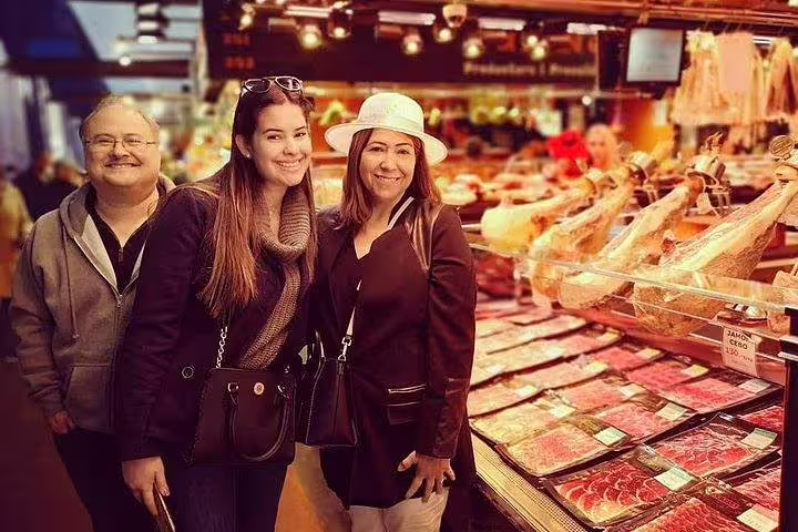 Tourists enjoying a food market in Barcelona, exploring local delicacies on a private tasting tour with Sagrada Familia access.
