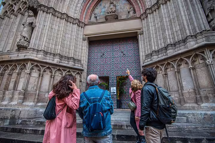 Tourists admire the detailed facade of a Gothic cathedral in Barcelona, highlighting its historical architecture.