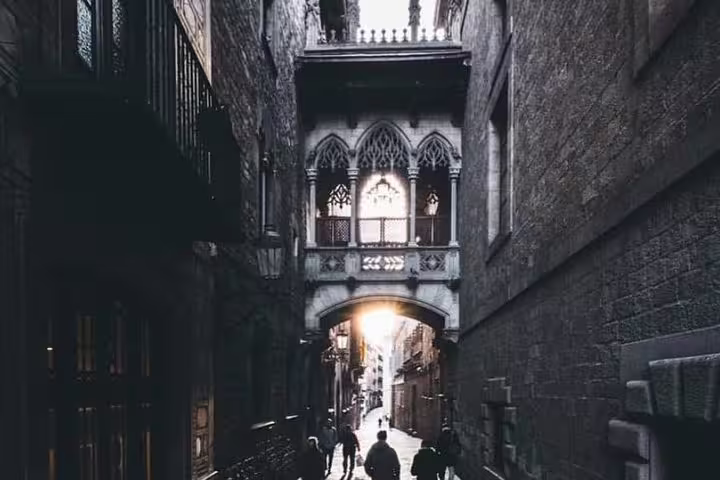 Historic Gothic Quarter street in Barcelona with archway and shadowy path, perfect for cultural city tours.