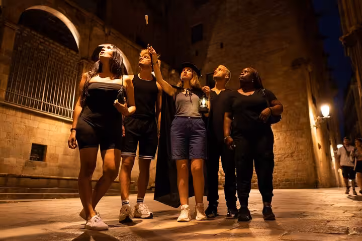 Tour group in Barcelona's Gothic Quarter, captivated by ghost stories during the evening tour.
