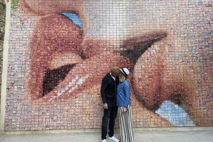 Couple standing before a vibrant mosaic mural in Barcelona, showcasing artistic elements of the city's Gothic Quarter.