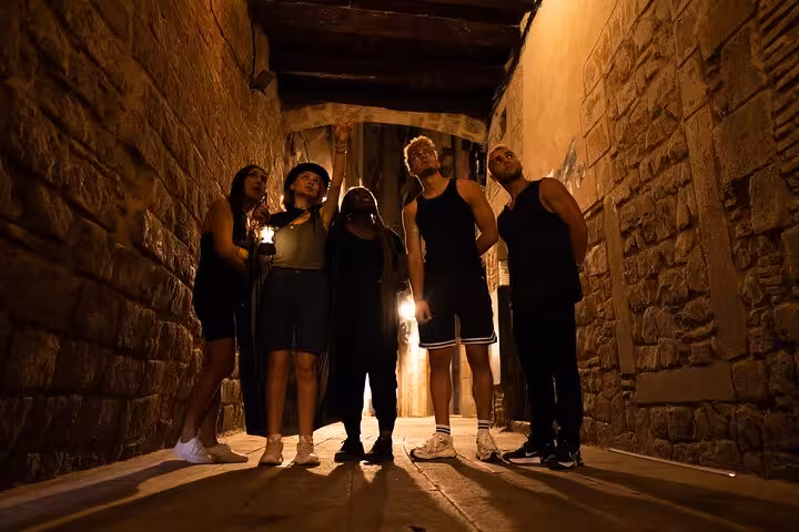 Group exploring a dimly lit alley during the Barcelona Ghosts and Legends Gothic Quarter Tour at night.