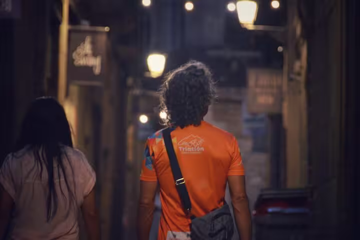Couple walking through a dimly lit historic alleyway in Old Town, experiencing the enchanting nighttime ambiance.