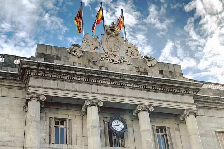 Barcelona's historic building with flags under a blue sky, featured in the Semi-Private Gothic and Sagrada Familia Tour.