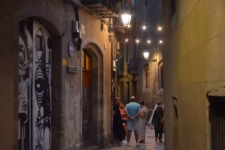 Visitors pause in a narrow, haunted alley adorned with street art during the Barcelona Ghosts of a Dark Past Walking Tour.