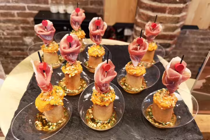 A selection of gourmet tapas with cured ham and vibrant garnish, showcased on a Barcelona food and drink tasting tour.