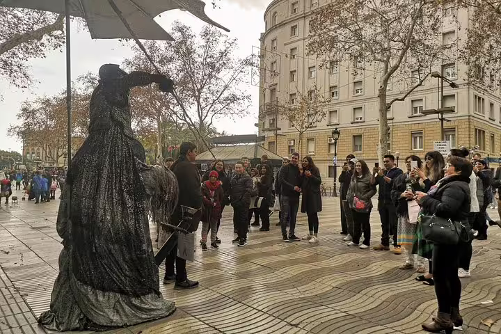 Tourists gather around a street performer on La Rambla in Barcelona, experiencing vibrant city culture on a guided private tour.