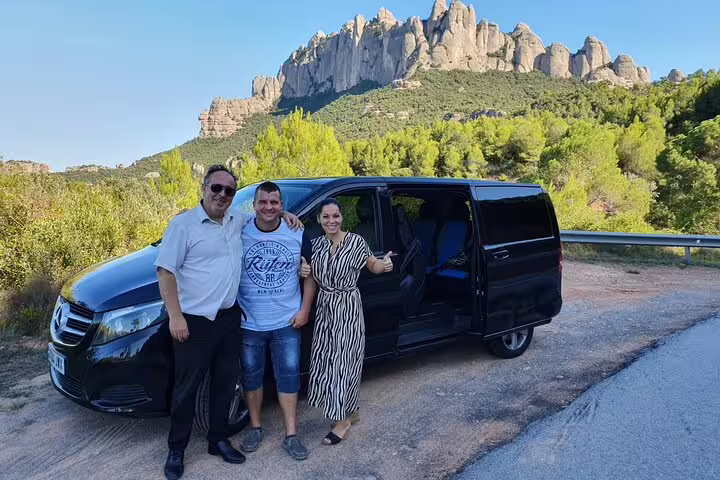 Tourists posing with a guide in front of a scenic view of Montserrat, part of the Barcelona City + Wine Celler Penedés Tour.