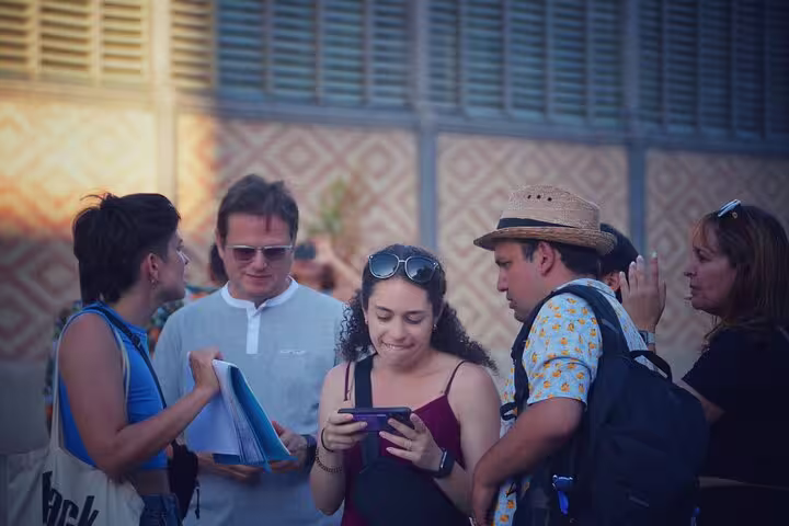 Group of tourists engaged in a guided tour in the historic Old Town, holding maps and smartphones for navigation.
