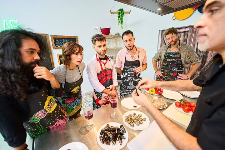 Participants attentively watch a chef demonstrate seafood preparation during the Ultimate Paella Cooking Class Experience.