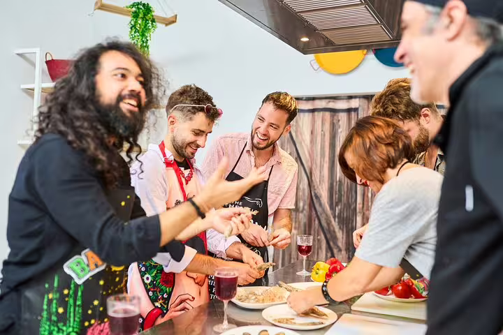 Group of diverse adults enjoying a hands-on paella cooking class, sharing laughter and learning in a vibrant kitchen setting.