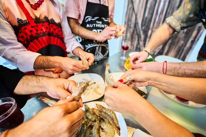 Participants prepare fresh shrimp together during a vibrant hands-on paella cooking class, enhancing culinary skills and teamwork.